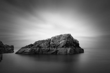 Howth, Dublin 'deki küçük kayalık ada, uzun süre açık bırakılmış, bulanık su ve bulutlar tarafından ele geçirilmiş, güzel sanatlara dönüştürülmüş siyah beyaz fotoğraf, İrlanda