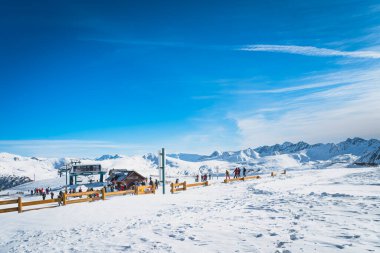 İnsanlar, kayakçılar ve snowboardcular dağın tepesindeki Andorra, El Tarter, Pirenes Dağları 'ndaki kayak asansörünün yanındaki yamaçlara çıkmaya hazırlanıyorlar.
