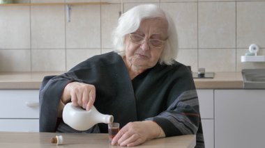 Yaşlı kadın bardağa içki döküyor..