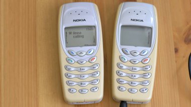 GDANSK, POLAND - 20 Mart 2022: bir masada iki eski cep telefonu. Şarj ediliyor..