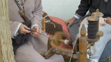 Kadın yün örüyor. Dönen tekerlek.
