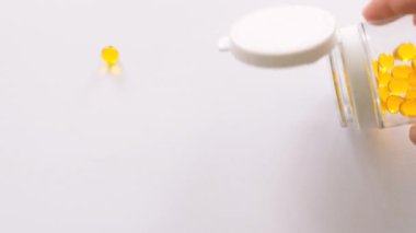 Vitamin D, A, E or omega 3 fish oil in the yellow pill. Golden capsules on the white background. Vitamin D, A, E or omega 3 fish oil concept.