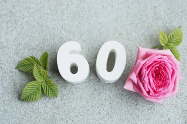 60 numaralı beton ve gri arkaplanda yaprakları ve kalpleri olan güzel bir gül.
