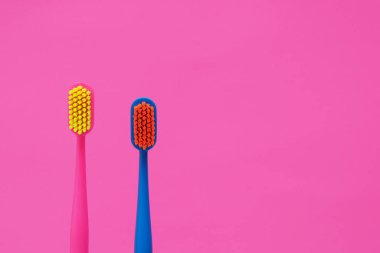 Pembe arka planda iki farklı renkte diş fırçası. Boşluğu kopyala