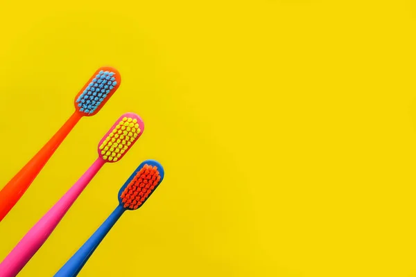 Three Multi Colored Toothbrushes Figurine Tooth Yellow Background Dentistry Advertising — Stock Photo, Image