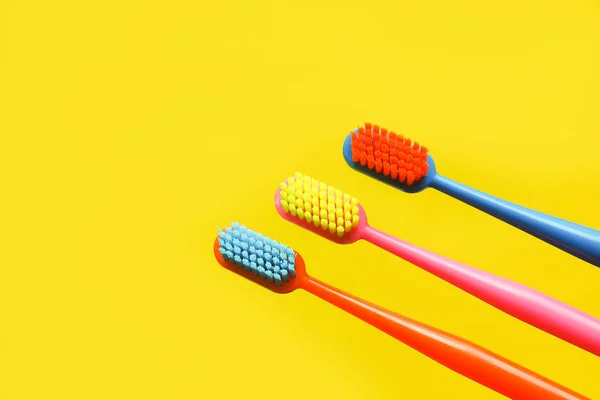 三个彩色牙刷和一个黄色背景的牙齿雕像 牙医广告的概念 复制空间 — 图库照片