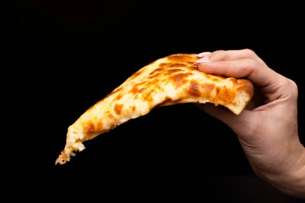 Elinde bir dilim peynirli pizza ve siyah bir arka plan.