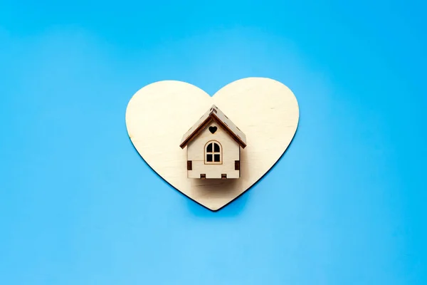Pequeña casa de madera y un corazón sobre un fondo azul. Dulce hogar. Imágenes de stock libres de derechos