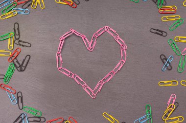 Koyu arkaplanda pembe ataçlardan yapılmış kalp sembolü