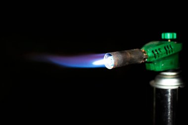 Karanlık bir arka planda yanan bir ocağı olan taşınabilir gaz silindiri. Yüksek kalite fotoğraf