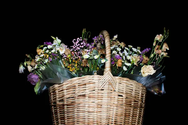 wicker basket with withered flowers in it on a dark background. High quality photo