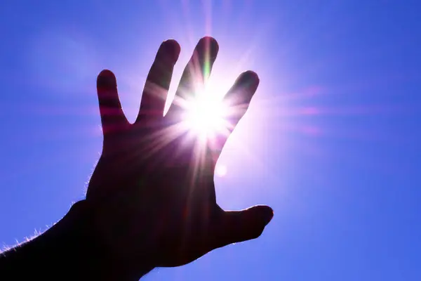 silhouette of a hand reaching for the sun. hand blocks the sun. High quality photo