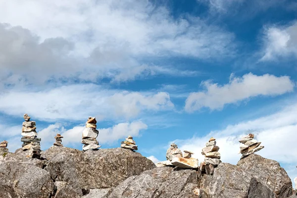 Yaz mevsiminde bulutlu gökyüzü olan dağdaki denge taşı kuleleri, İrlanda, Connemara.