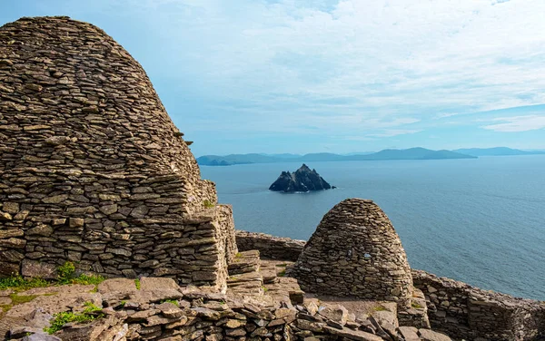 Yaz mevsiminde deniz kıyısındaki Skellig Adası 'ndan (ön planda Hristiyan manastırı kalıntıları) manzaralı nefes alıyor. UNESCO Dünya Mirası Sitesi, İrlanda