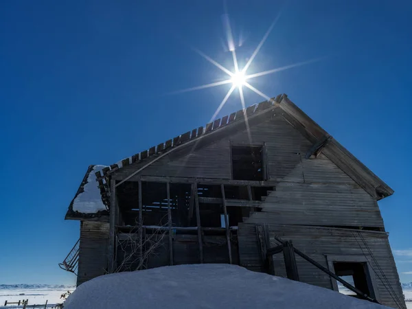 Unusual angle on an abandon home with pile of snow and sun star