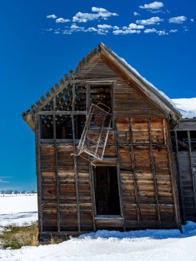 Harap olmuş bir çiftlik evinin penceresinden sarkan yatak.