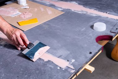 Pool table slate is sealed using a puddy knife