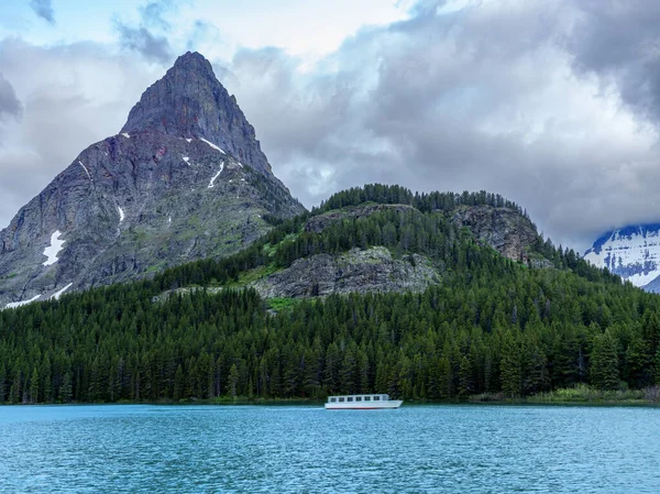 Motion blur boat speeds across a lake in Glacier National Park