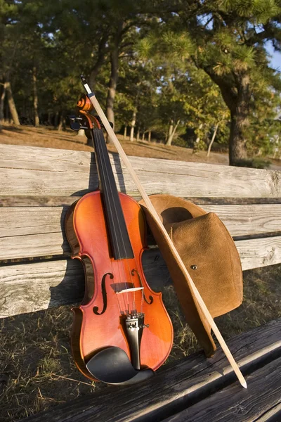 Chapéu de violino e cowboy em um banco de parque — Fotografia de Stock