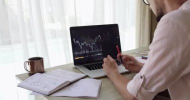 Kırpılmış sakallı bir analist, düşen ticaret çizelgesine baktığı için gergin.