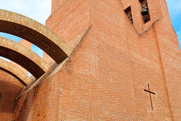 Çan kulesi ve çanları olan modern tuğla kilise.
