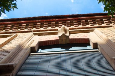 Neo-Mudejar facade of a public school with a sign indicating in Spanish 