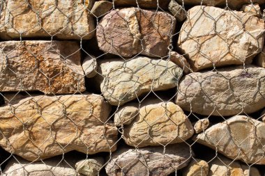 Retaining wall of irregular stones with metal mesh