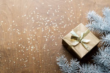 Tahta bir masanın üzerinde altın bir hediye kutusu. Yıldızlar şeklinde altın işlemeli. Köknar dalları arasında. Yüksek kalite fotoğraf