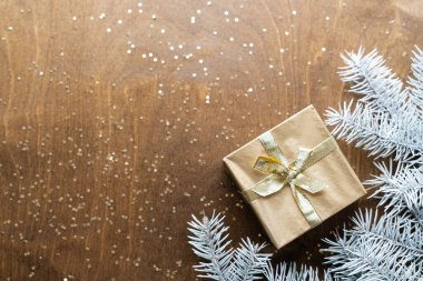 Tahta bir masanın üzerinde altın bir hediye kutusu. Yıldızlar şeklinde altın işlemeli. Köknar dalları arasında. Yüksek kalite fotoğraf