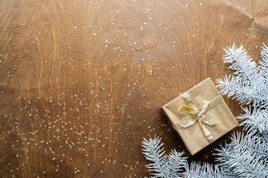 Tahta bir masanın üzerinde altın bir hediye kutusu. Yıldızlar şeklinde altın işlemeli. Köknar dalları arasında. Yüksek kalite fotoğraf