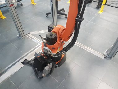 6 axis robot arm in a jail in a electromechanical lab. 6 degrees of freedom robot arm. Orange robot arm. Robot arm in a security jail.Cables and servos clipart