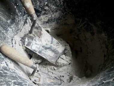 Bir taş kovasında çimentoyla iki mala.