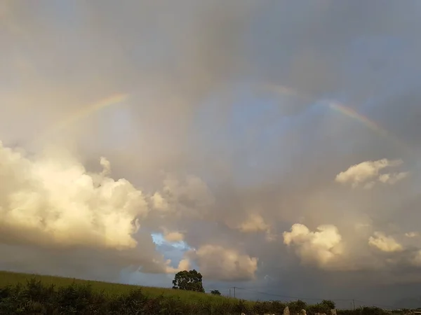 彩虹从草地上穿过多云的天空 — 图库照片
