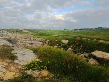 Üç kız bulutlu bir günde uçurumun kenarında yürüyorlar.