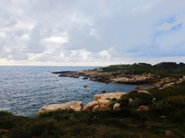 Birçok erkek bulutlu bir günde güzel bir sahilde yürür.