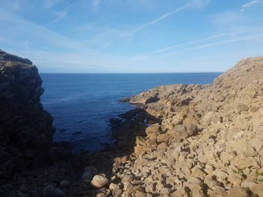 Mavi deniz tarağı. Gökyüzü mavi gökyüzünde yol alıyor. Uçurumdaki büyük kayalar