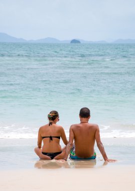 Sahilde oturan genç mutlu çift.