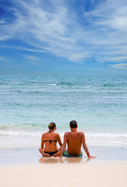 Jovem casal feliz sentado na praia . — Fotografia de Stock