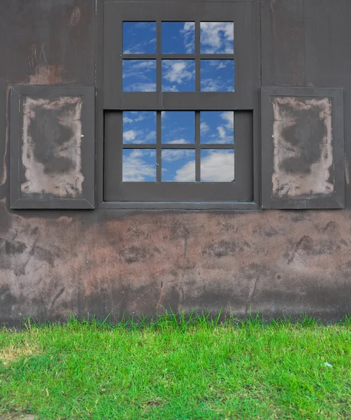 Fönster på viftande brun vägg med gräs — Stockfoto