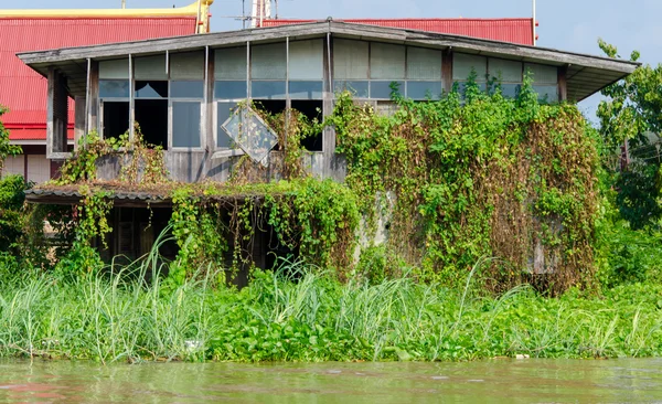 Заброшенный дом заросший травой на набережной — стоковое фото