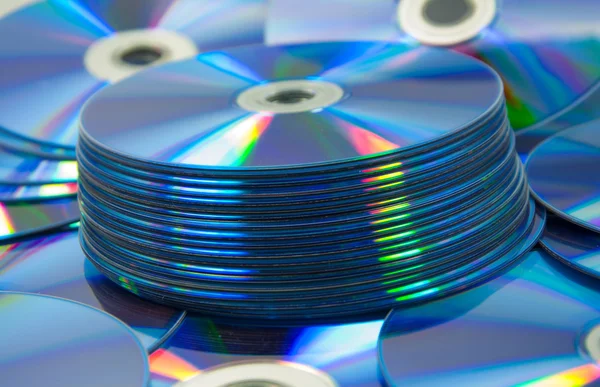Conjunto de discos compactos coloridos de DVD espalhados em uma mesa — Fotografia de Stock