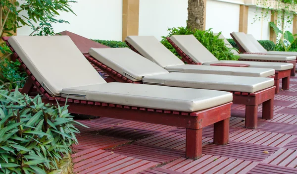 Пляжные стулья возле бассейна в тропическом курорте — стоковое фото