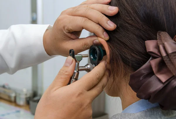 Otorrinolaringólogo revisando el oído del paciente usando otoscopio con un inst —  Fotos de Stock