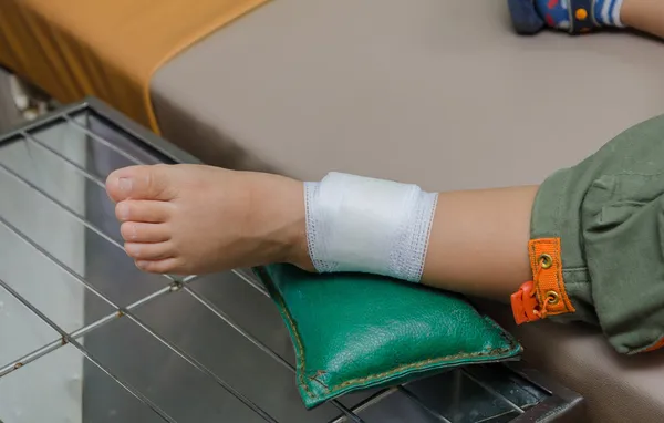 Barn pojke med bandage på benet och liggande sjukhussäng — Stockfoto
