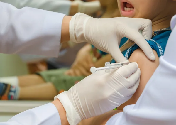 Médico inyectar la vacuna en el brazo del niño — Foto de Stock