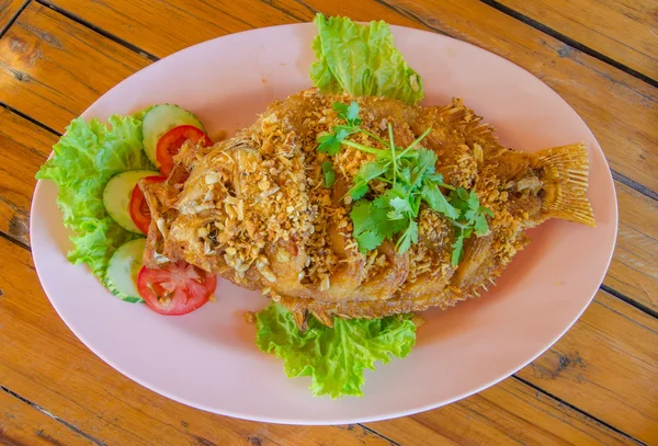 Fried red tilapia fish with crispy garlic on the wood table — Stock Photo, Image