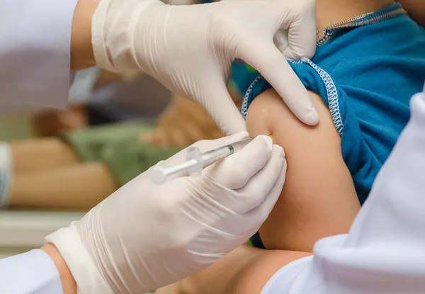Médico administrar a injeção de vacina ao braço do menino Imagens De Bancos De Imagens Sem Royalties