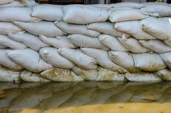 Sacchi di sabbia bianchi per la difesa dalle inondazioni ed è riflesso acqua marrone — Foto Stock