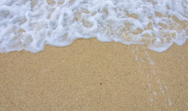 Ola de burbujas de mar en la playa de arena — Foto de Stock