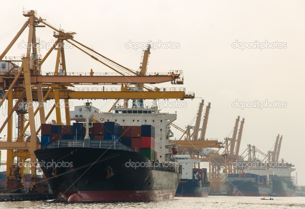 Container Cargo freight ship with working crane bridge in shipya